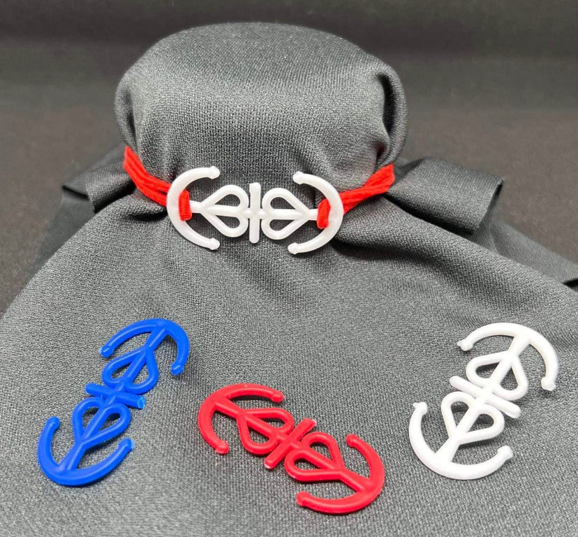 Picture with dark cloth background, displaying four 'my anchor hooks', of colors red, white, and blue. Demonstrating that 'my anchor hooks' may be worn as a bracelet, hair tie, or fashion wardrobe accessory.